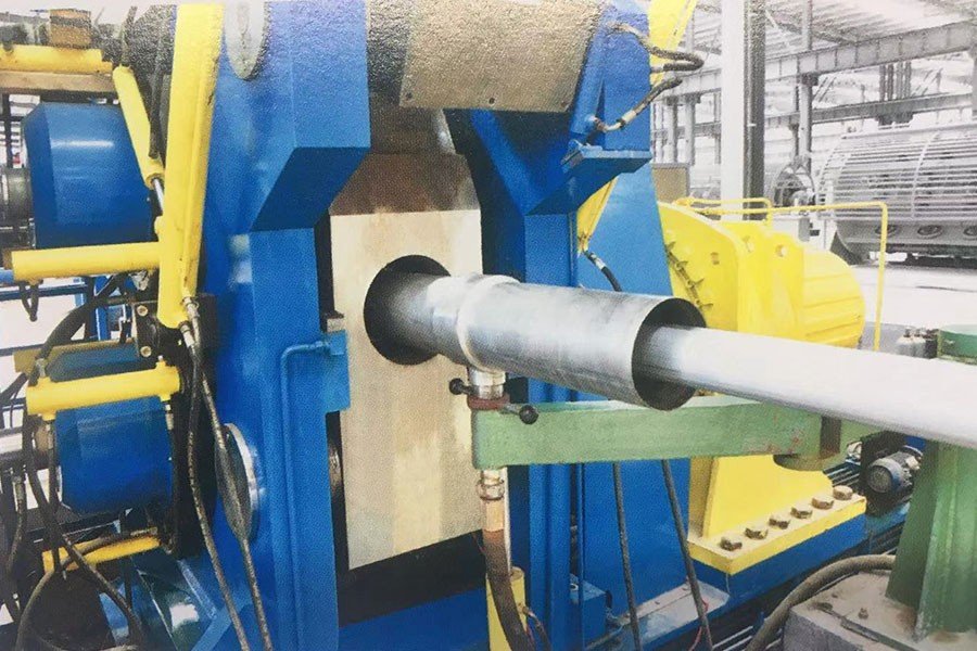 Close-up of aluminum sheath forming section on RLB continuous extrusion line – seamless aluminum tube being applied around cable core with water-cooling protection